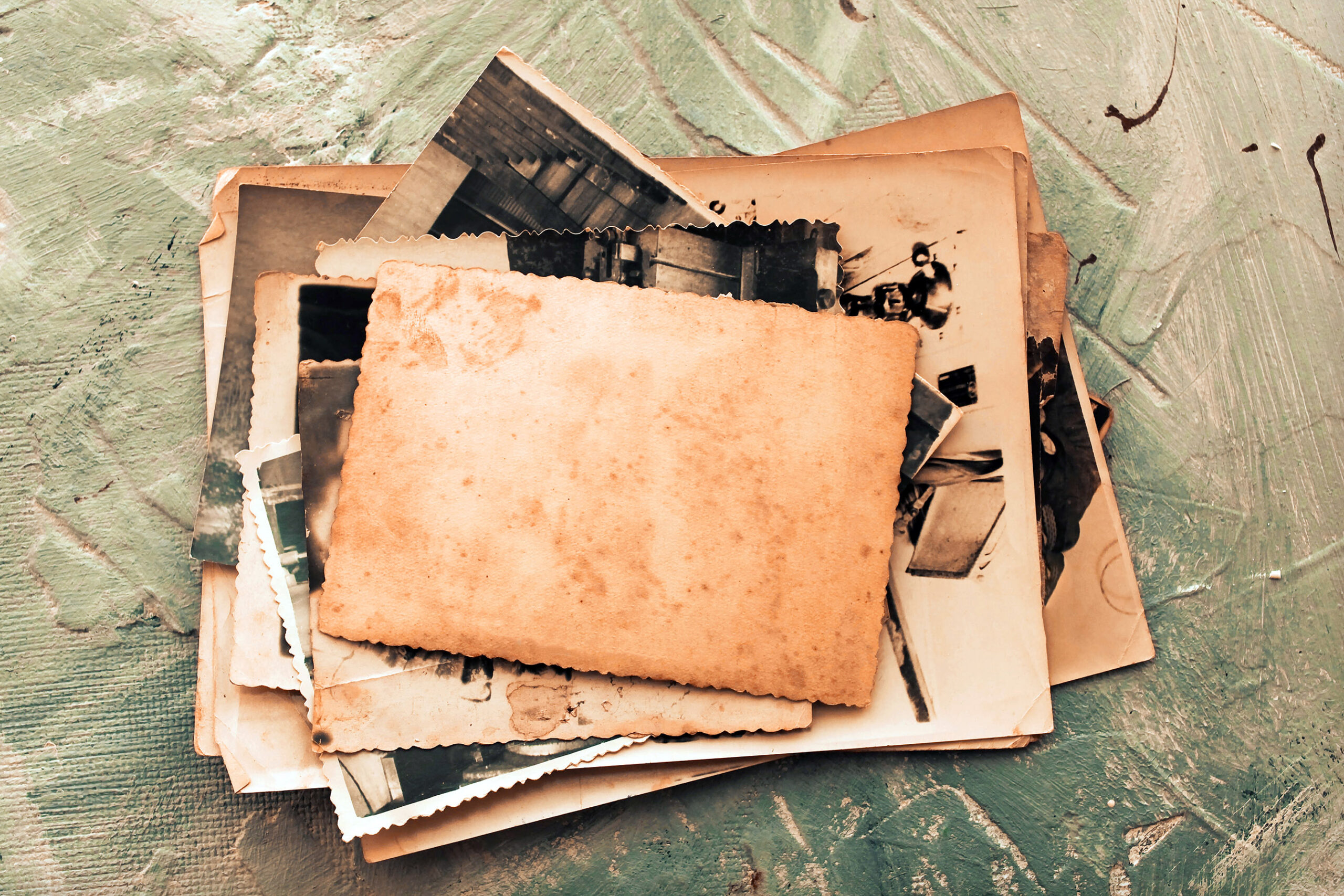 Stack old photos on grey background. Postcard rumpled and dirt